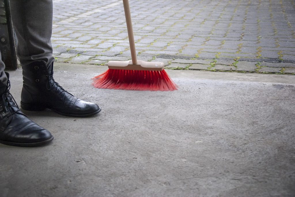 Person sweeping entryway – how to get rid of salt stains on floors
