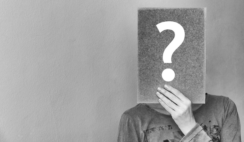 Person holding a question mark sign in front of their face