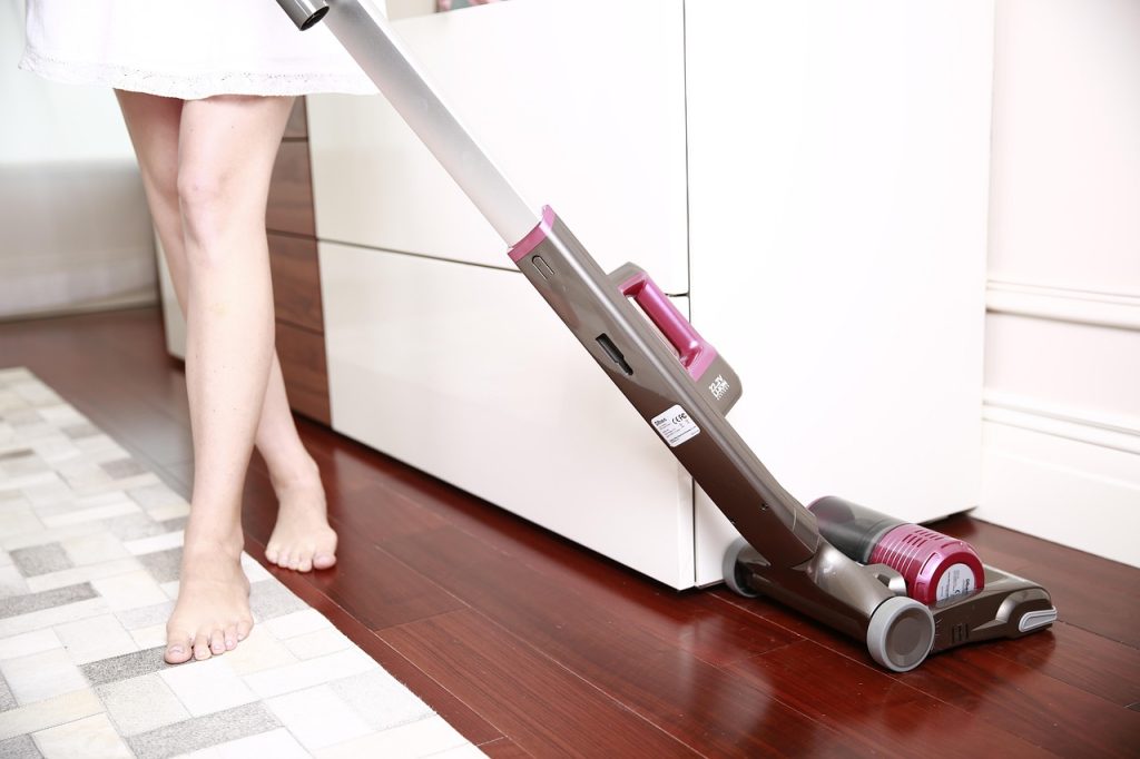 Person vacuuming hardwood floor with modern floor cleaning supplies
