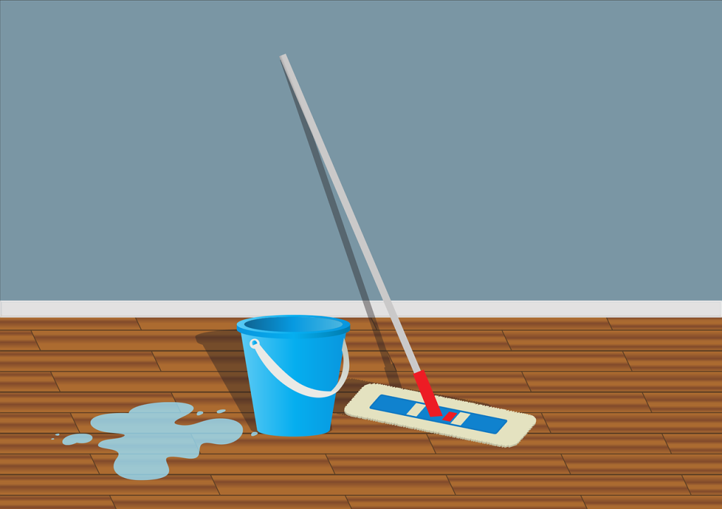 Flat mop, blue bucket, and water spill on a wooden floor against a blue wall