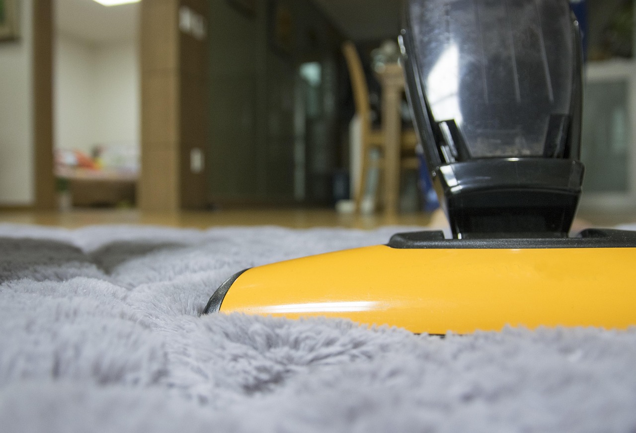 Vacuum cleaning a soft high-pile carpet in a modern home, showcasing one of the latest carpet trends for cozy and comfortable living spaces.