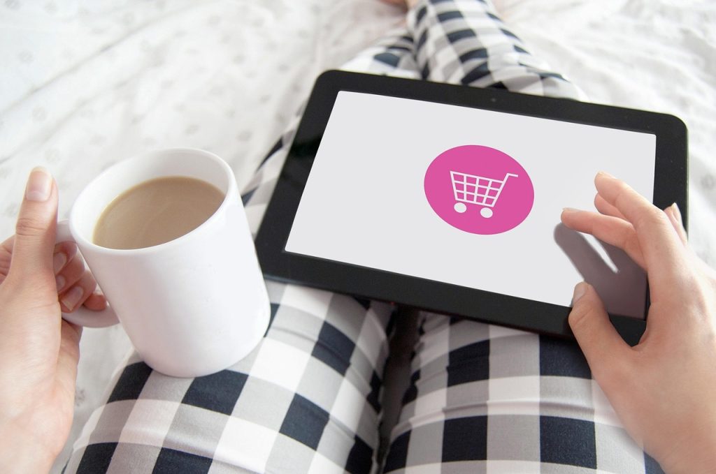 Woman holding a cup of tea while browsing a tablet, researching the best floor mop for tile floors.