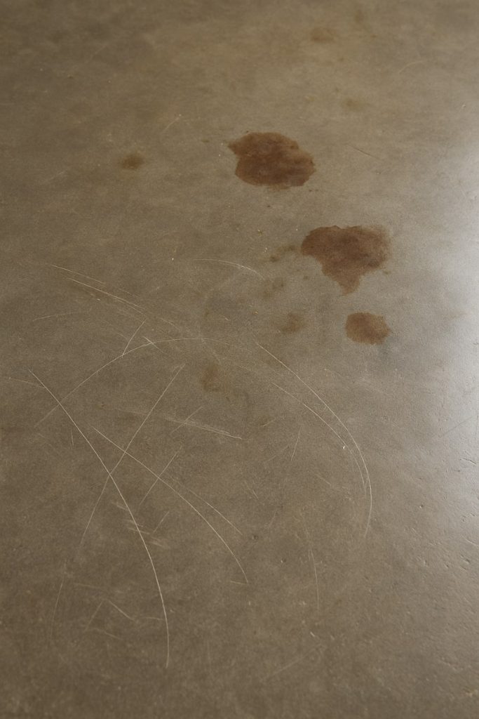 Scratched and stained surface caused by dragging furniture and ignored spills.