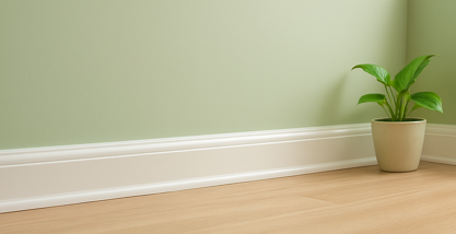 Freshly cleaned white baseboard beside a green houseplant in a bright room.